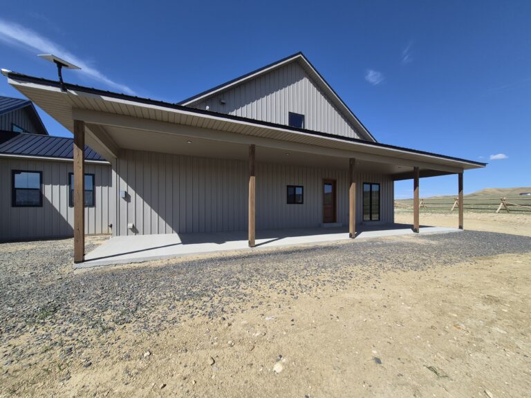 Covered Porch on Covered porch on a custom Wyoming home with textured taupe metal soffit, metal siding, and wood support posts.