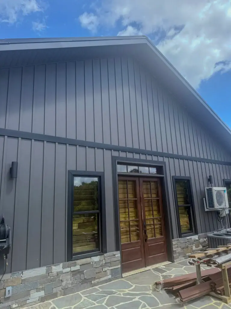 Textured Charcoal Metal Batten siding installed on a custom home's exterior with black trim and stone veneer accents.